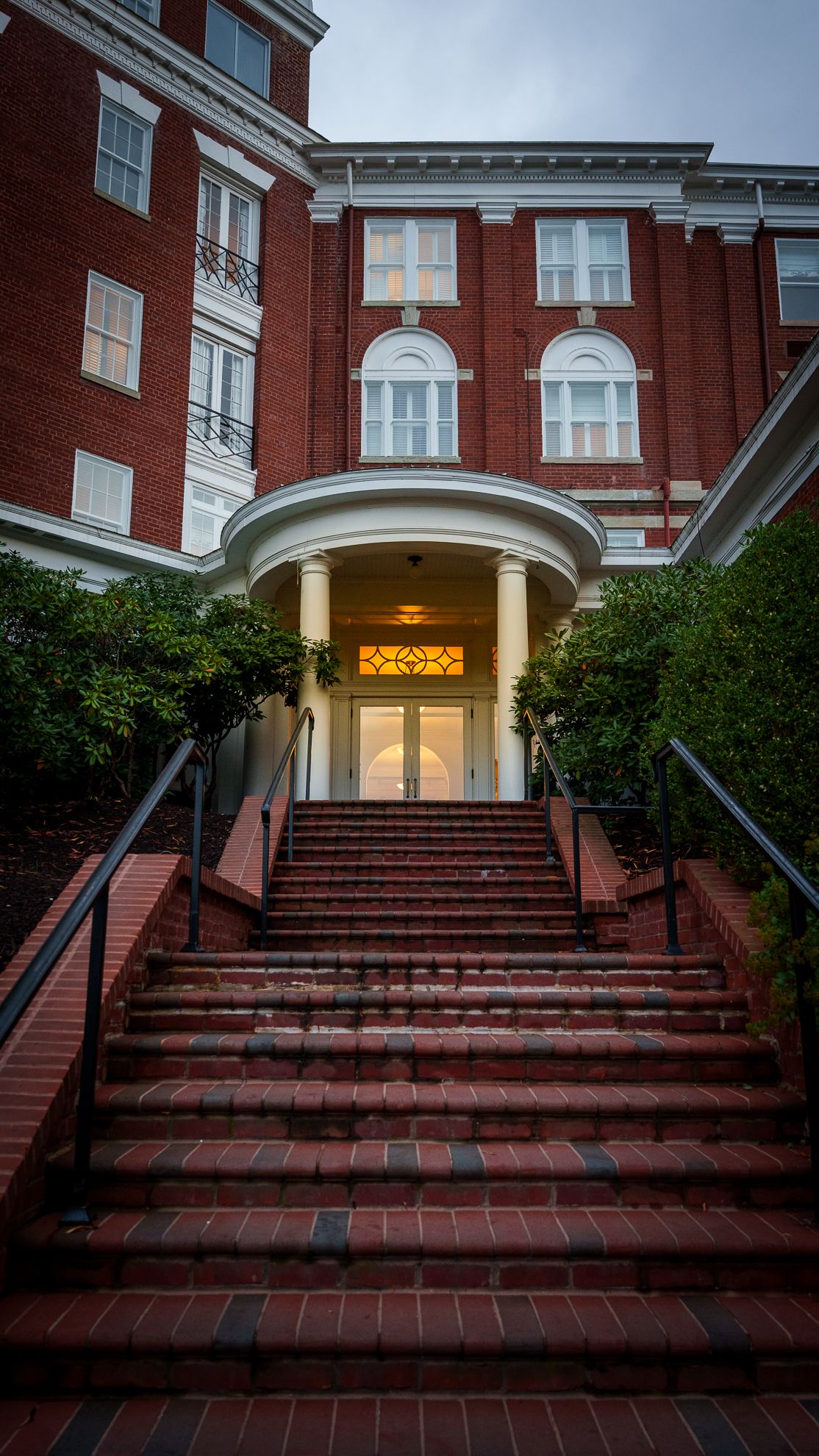 Brick steps rising to a lit entrance archway of a resort hotel at dusk