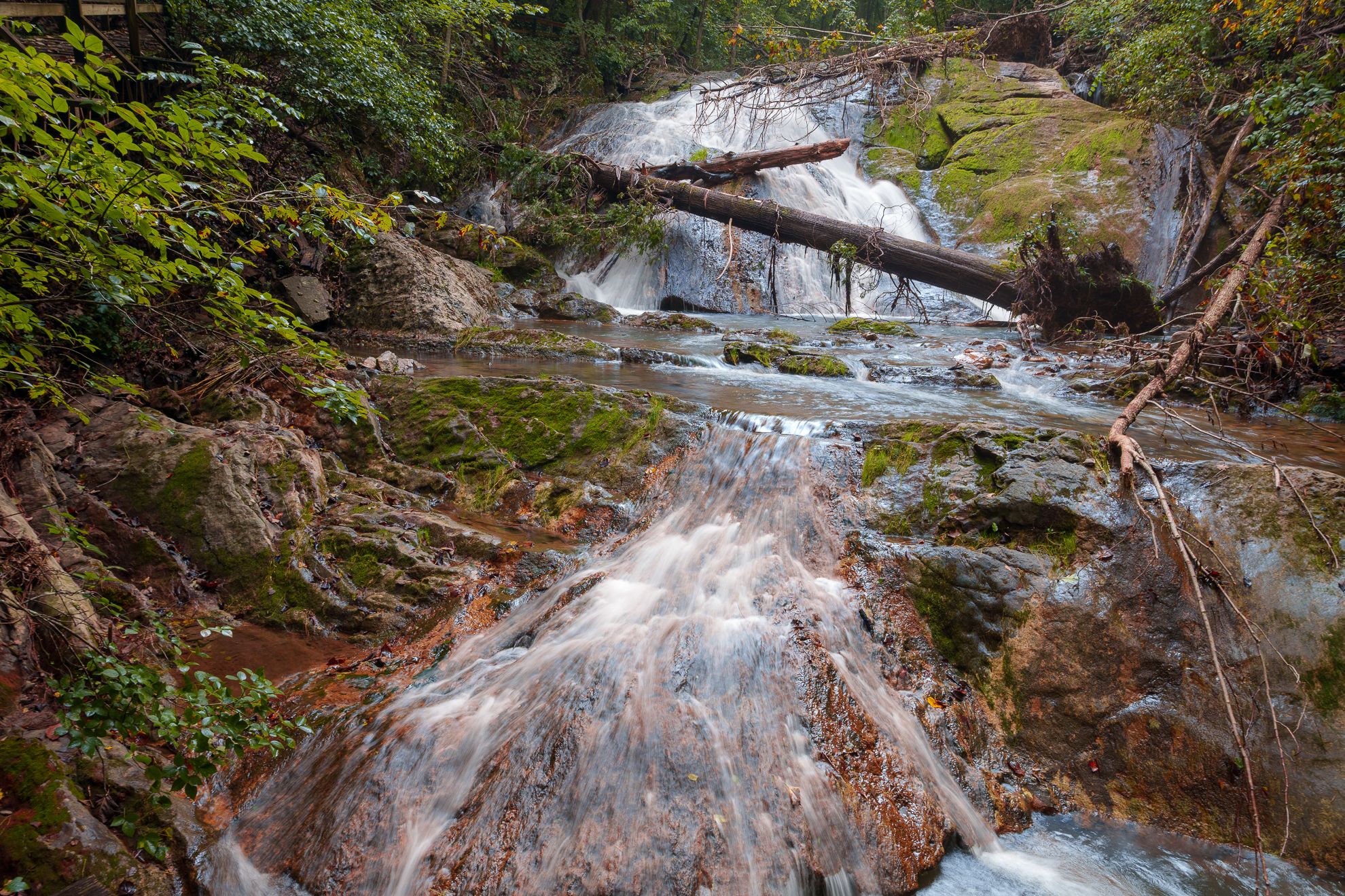 A long stepped waterfall with a fallen log spanning the current