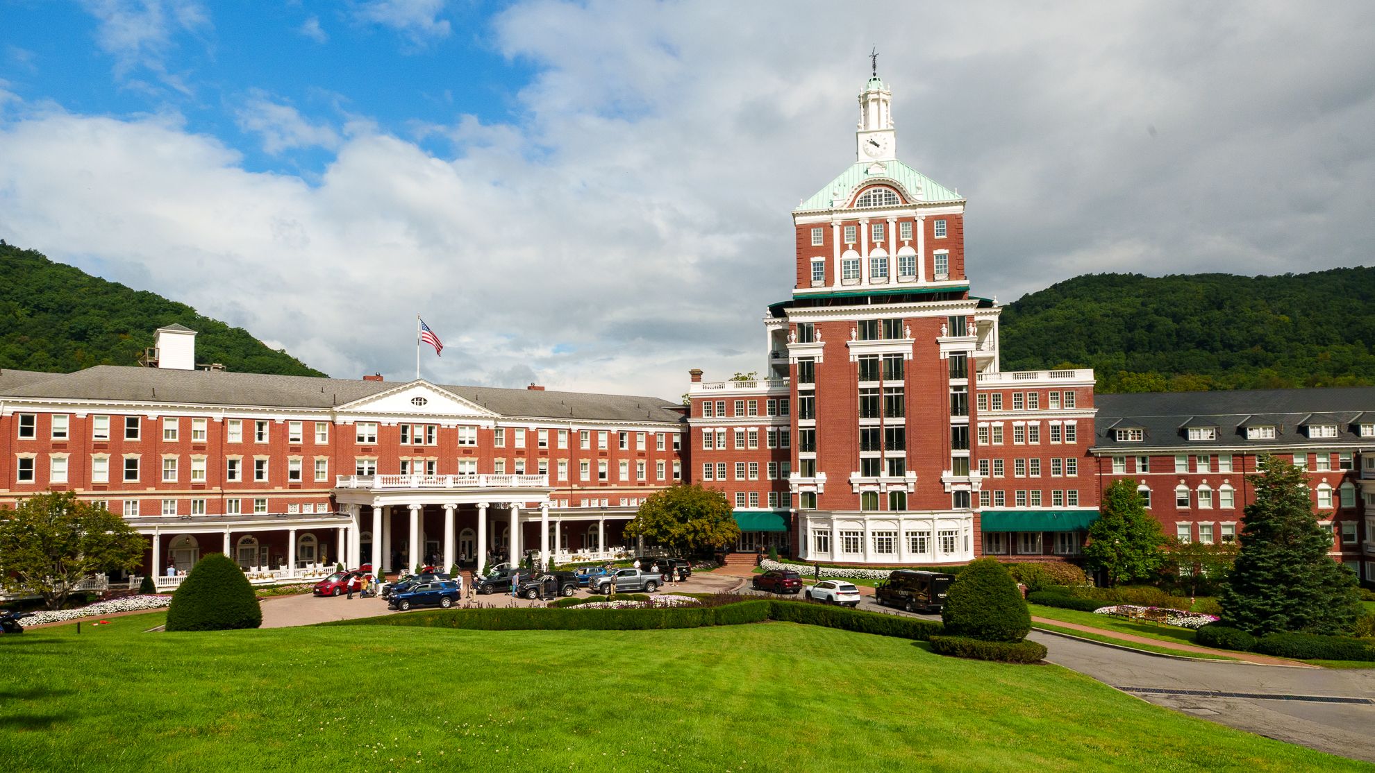 A grand red-brick resort hotel and clock tower under a clear blue sky