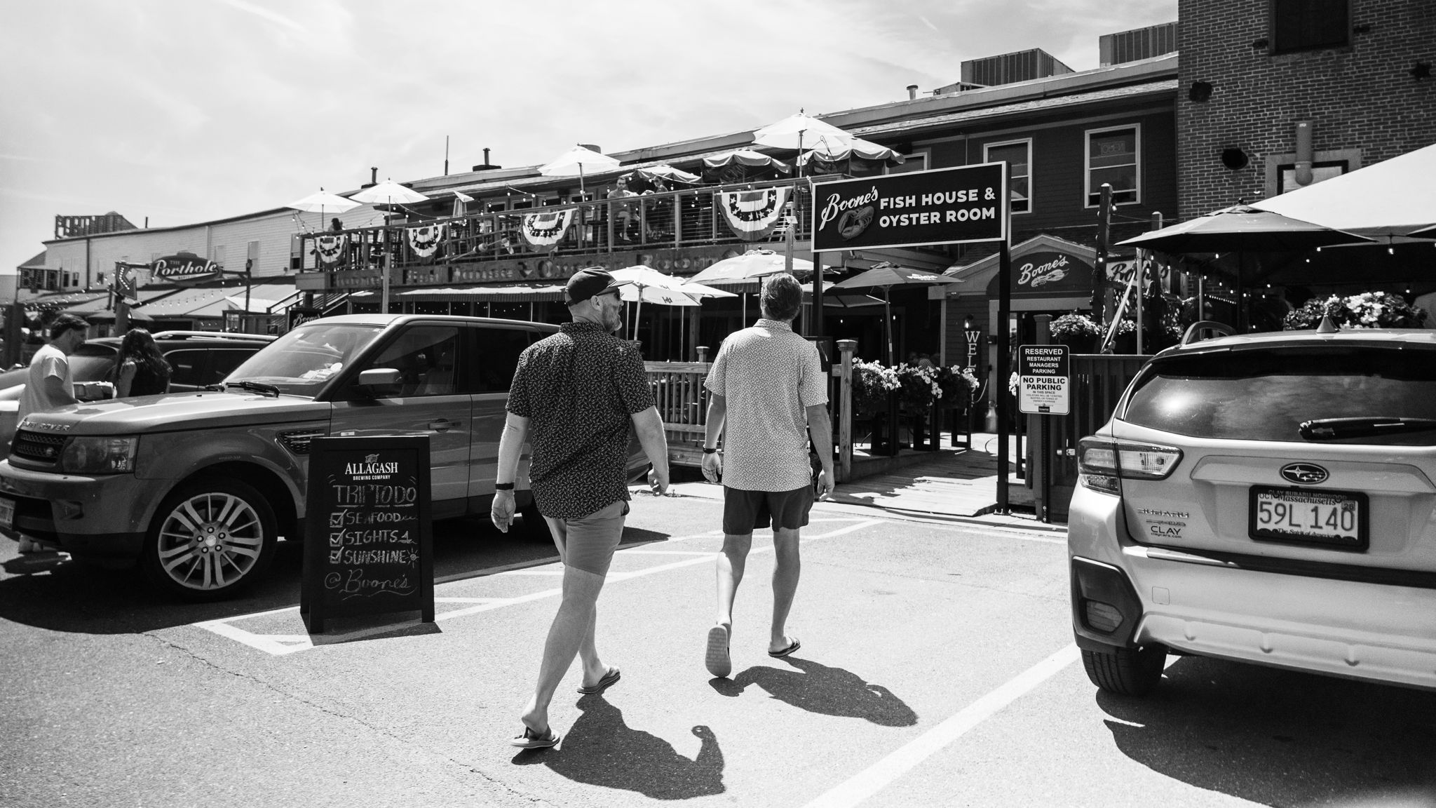 A busy Old Port street of fish houses and umbrellas, black and white