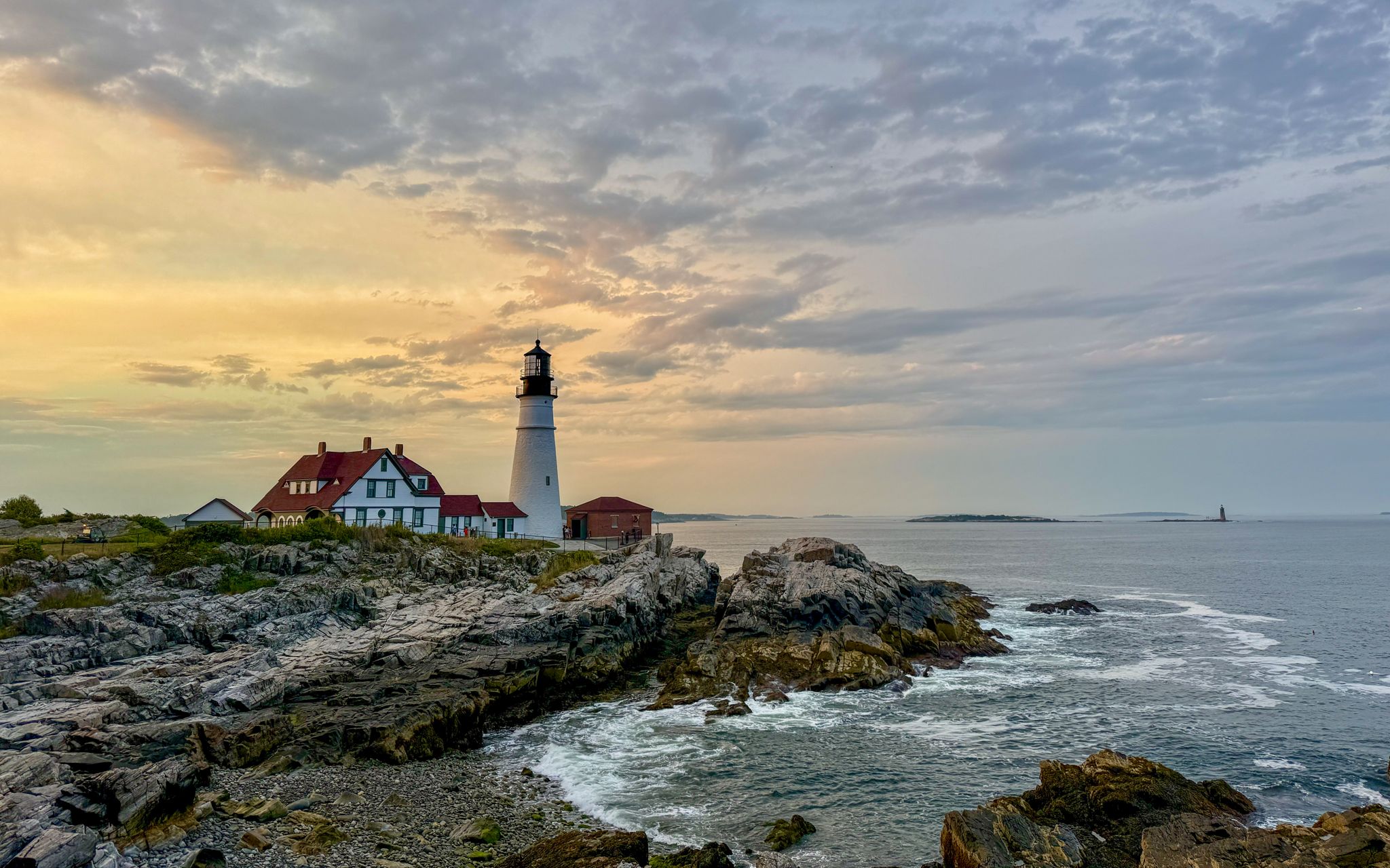 Golden sunrise behind Portland Head Light and its keeper's house